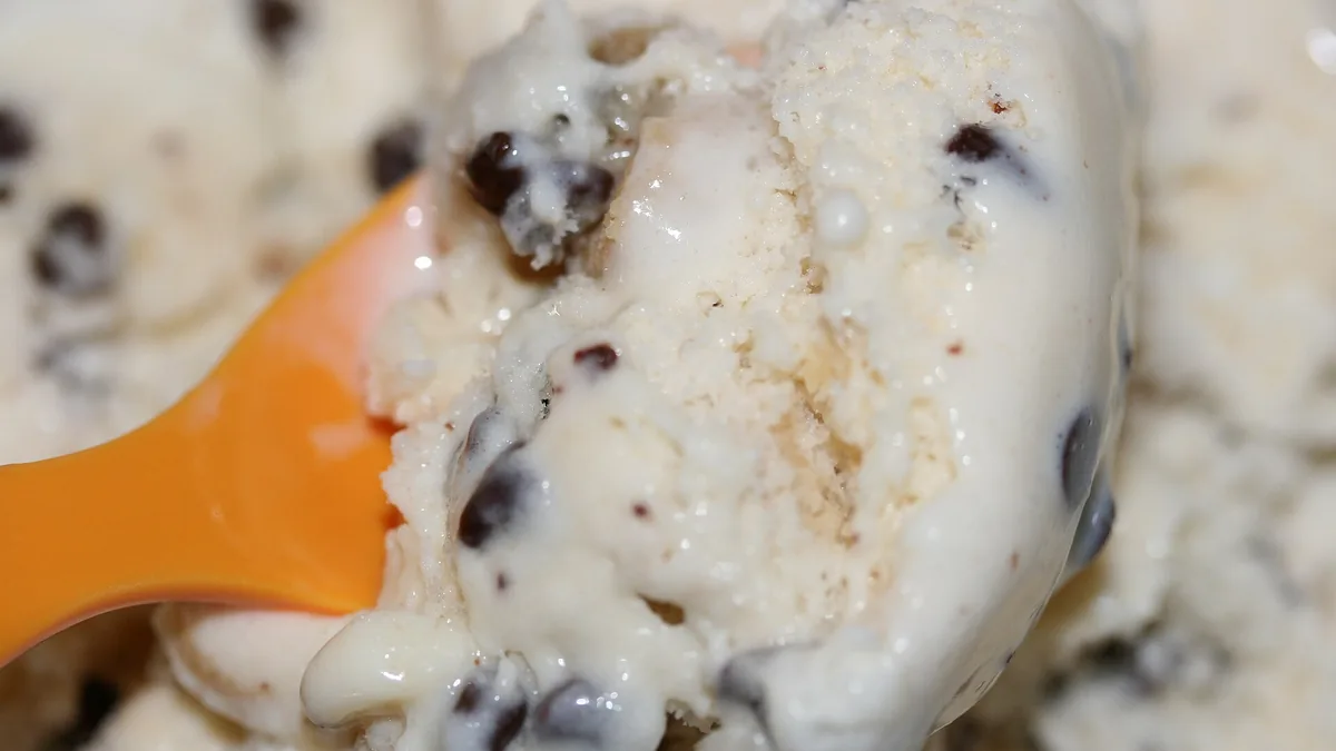 Close-up of creamy cookie dough ice cream with chocolate chips and an orange spoon