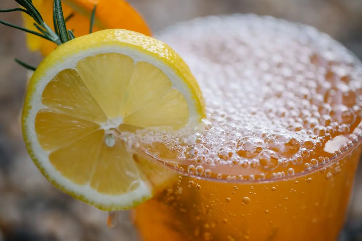 Bubbly orange citrus drink with a lemon slice on the rim