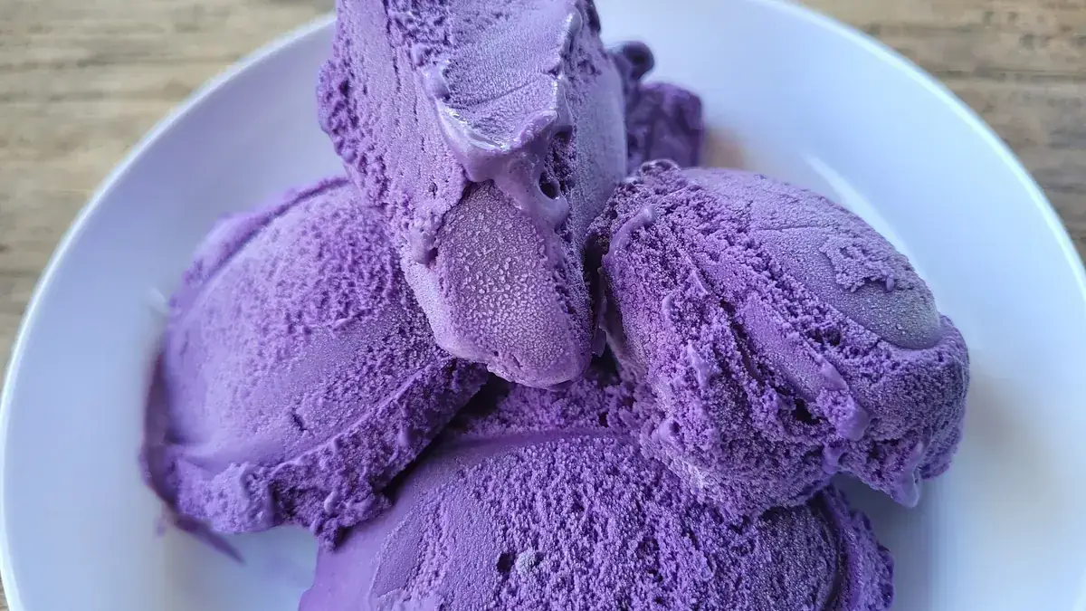 Scoops of vibrant purple ube ice cream served in a white bowl