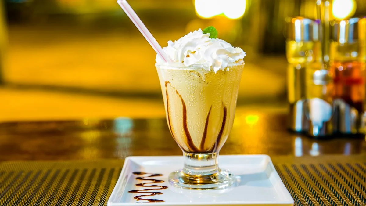 Glass of creamy vanilla milkshake topped with whipped cream